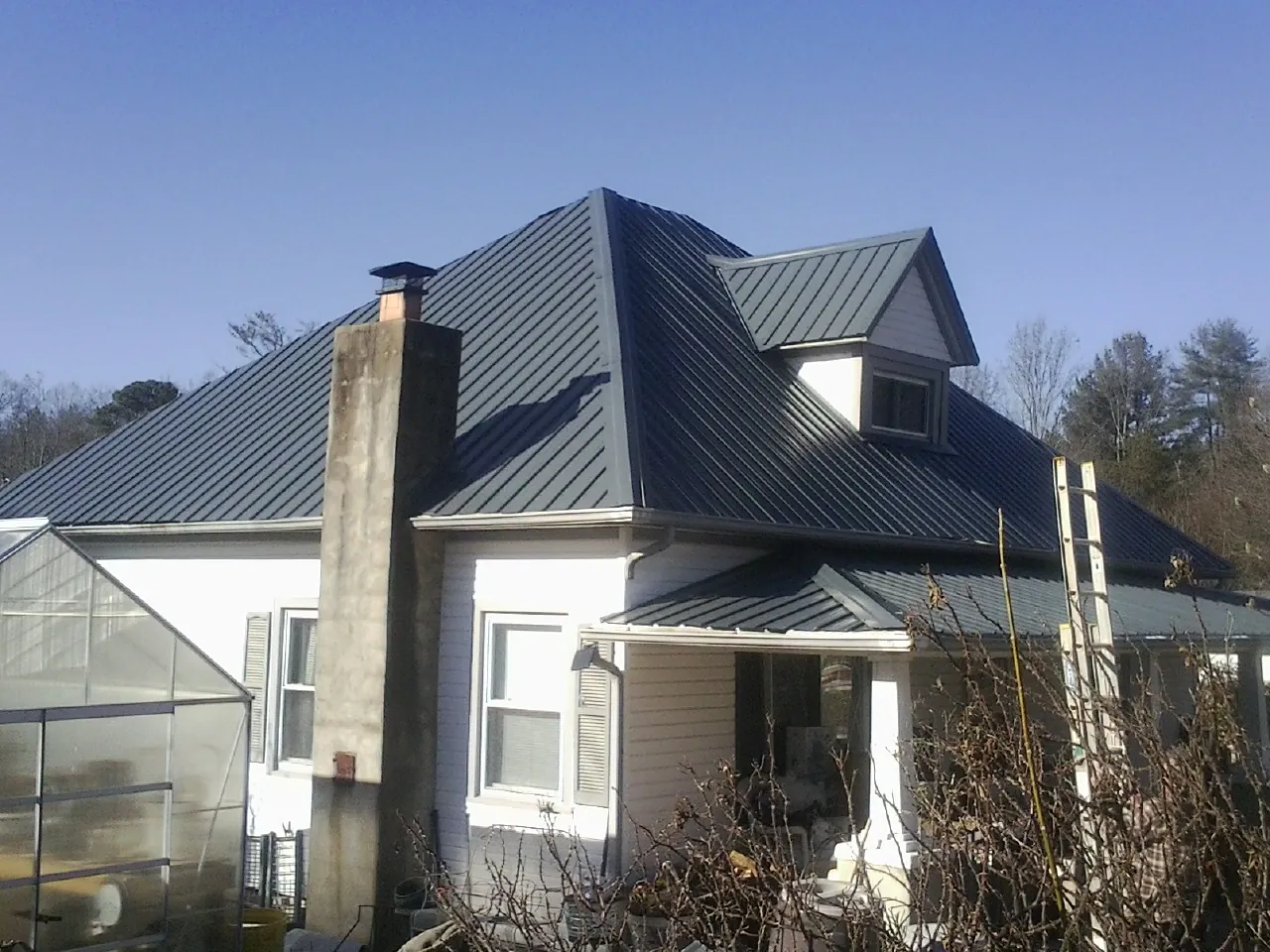 Dark blue standing seam metal roof on a white farmhouse with dormer — Slate & Tile Roof Repair by Roofing Brothers in Clear Spring
