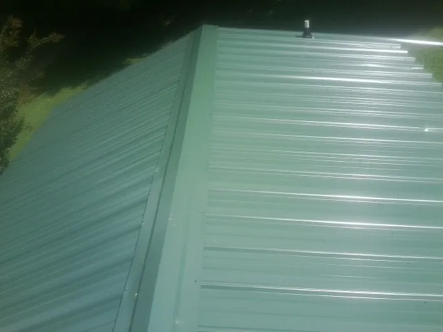New green metal panels meeting at the ridge of a roof — Flat Roof Repair work by our crew in Clear Spring