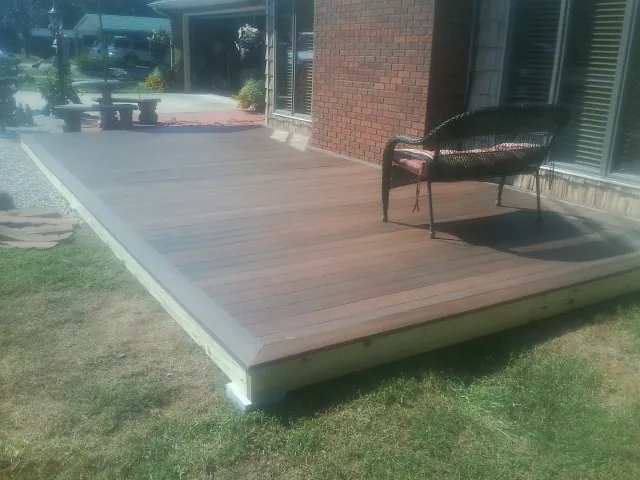 New wood deck and wicker chair beside a brick house in Clear Spring