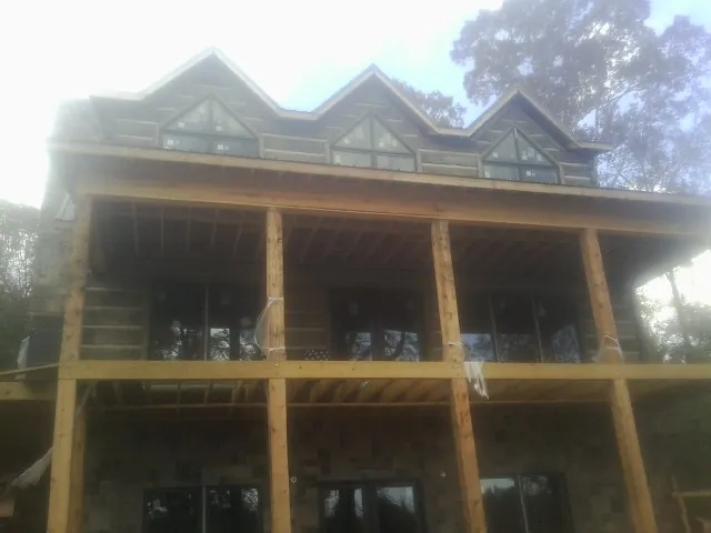 Dormers and porch framing on a large log home under construction — Roof Coating work by our crew in Clear Spring