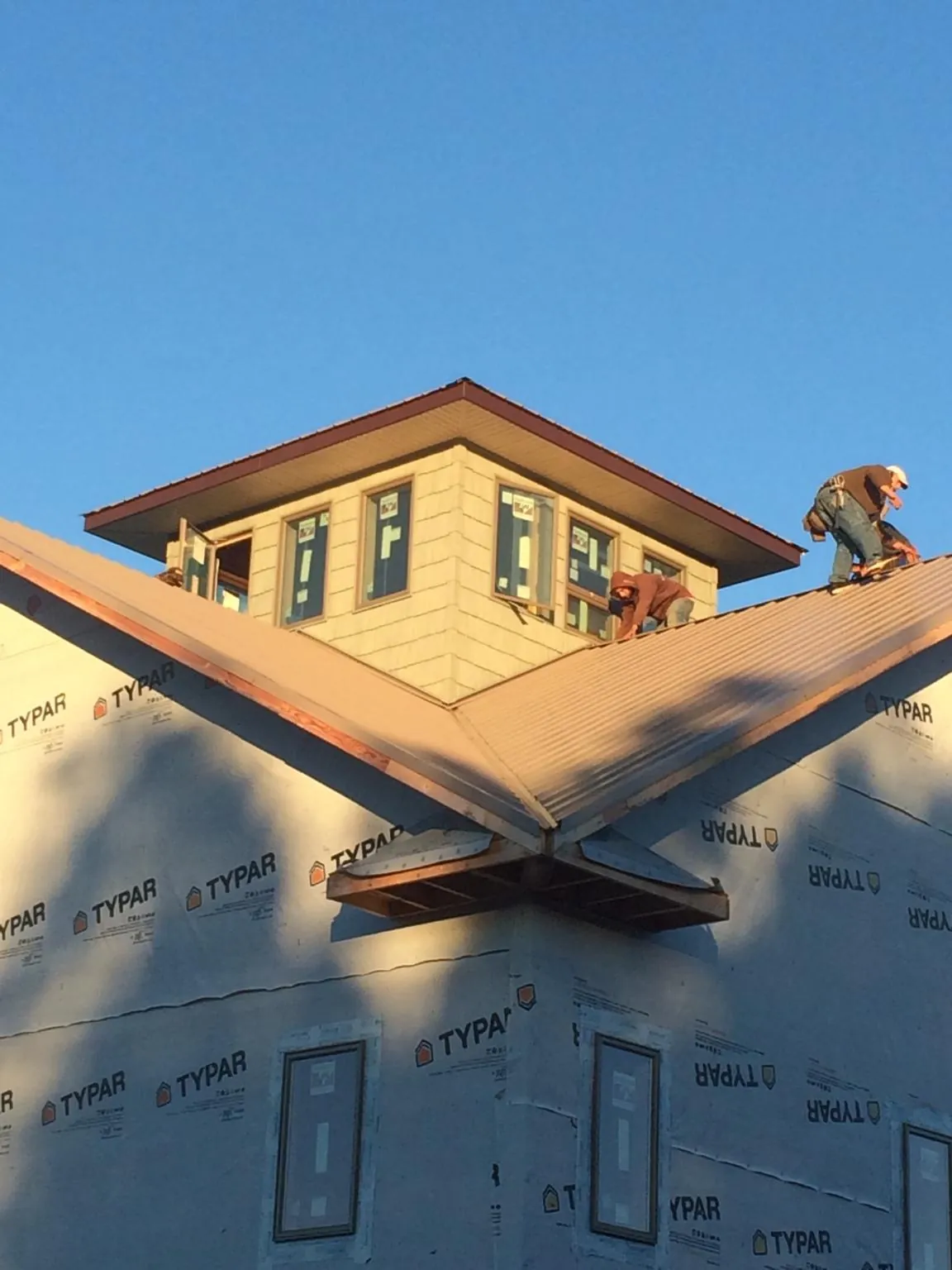 Roofers working around a rooftop cupola on a new metal roof at sunset — Roof Waterproofing in Clear Spring by Roofing Brothers